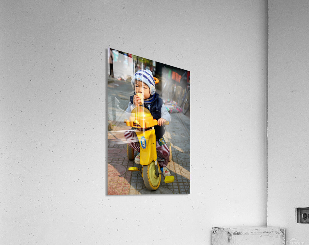 Child enjoys snack while riding tricycle in Hanoi streets Acrylic Print