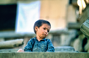 Sad boy sitting on stairs in Lahore Pakistan during the day by Marco Brivio