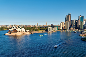 Sydney Opera House and city skyline with boats on water.
