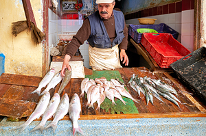 Fishmonger at work in Meknes market selling fresh catch of the d