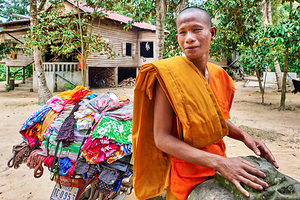 Monk with colorful textiles on a motorcycle.