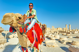 Camel driver in ancient Palmyra leading a tourist ride