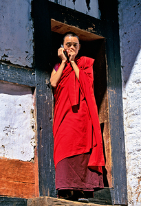 Monk in red robes on cell phone.