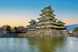 Matsumoto Castle stands by the water at sunset in Japan