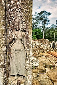 Ancient Apsara carving on weathered temple wall.
