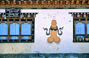 Phallus painting on a building wall with windows and shop sign.