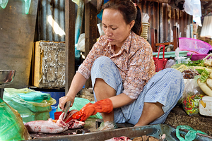 Market woman cleaning fish.