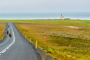Cyclists riding near Kollafjardarnes Church in Iceland