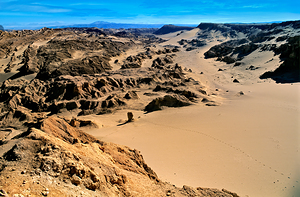 Vast desert valley sand dunes and sculpted rock formations.