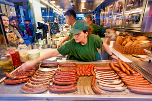 Sausages cooking at a busy street food stand.