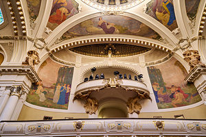 Ornate theater interior with murals sculptures and balcony.