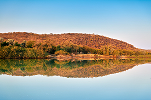 Okavango river reflects dusk sky in Kavango region of Namibia