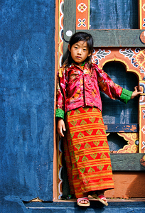 Young girl in vibrant traditional dress by ornate window.