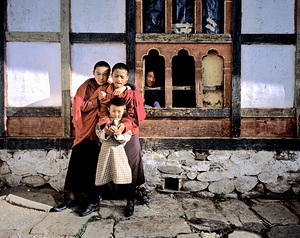 Children embracing one holding toy gun outside traditional bui