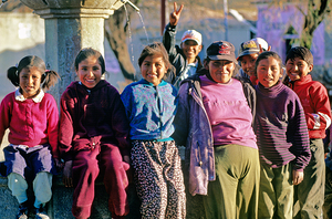 Smiling children and youth gather by a fountain. by Marco Brivio