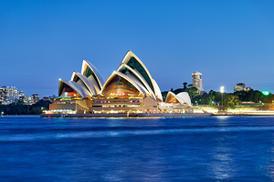 Sydney Opera House illuminated at dusk over the harbor. by Marco Brivio