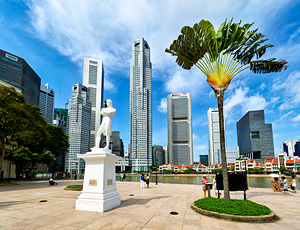 Visitors gather at Raffles landing site with city skyline in Sin