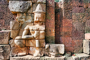 Ancient Khmer stone carving on a weathered temple wall.