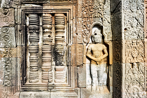 Ancient temple wall with intricate stone carvings and a figure.