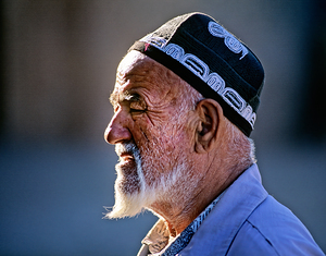 Elderly man in traditional clothing walks in Khiva Uzbekistan