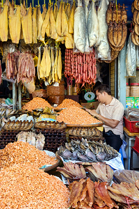 Dried fish shrimp and sausages for sale at market stall.