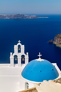 Blue domed church and bell tower overlooking Santorinis caldera