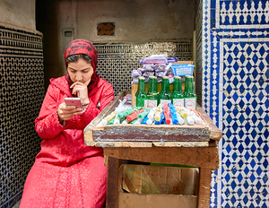 Woman using smartphone in Fez Medina while sitting by a stall