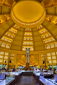 Grand domed market interior with central clock and bustling stal