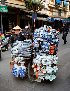 Woman transports pottery on a bicycle in Hanoi streets by Marco Brivio