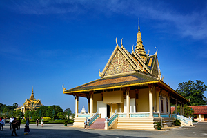 Ornate Cambodian temple under clear blue sky with visitors.