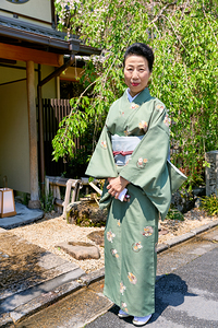 Woman in kimono stands outside in Kyoto during a sunny day