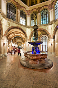 Ornate indoor arcade with fountain and people.