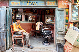Barber shop scene in Bikaner Rajasthan showing young customer w