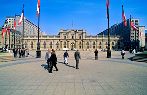 Chilean flags grand building and people in a city plaza. by Marco Brivio