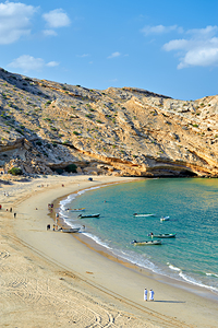 Muscat Oman beaches with boats and people walking along shore