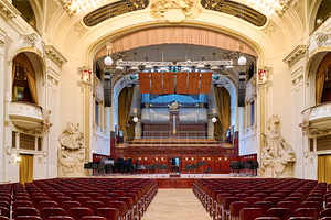 Grand concert hall with organ and empty seats.