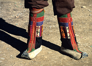 Colorful traditional boots on a person in Tibets landscape