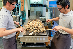 Grilling oysters at a restaurant in Miyajima Hiroshima Japan