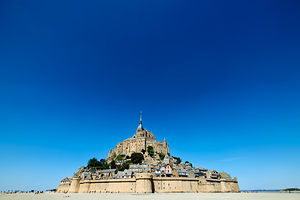 Mont Saint Michel rises above the ground during low tide in Norm