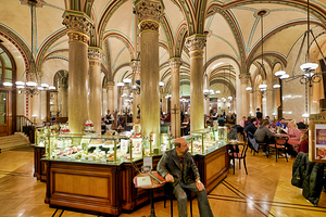 Elegant cafe interior with customers pastries and a statue.