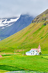 Bolungarvik church stands among green hills and mountains