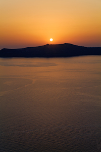 Golden sunset over ocean with silhouetted island.
