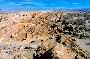 Dramatic desert landscape with eroded formations under a blue sk