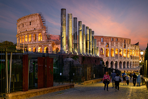 Visitors walking near the Colosseum in Rome at dusk