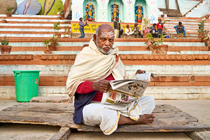 Man reads newspaper by river in Varanasi India