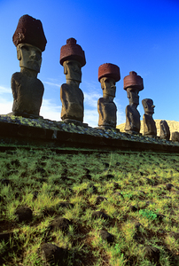 Row of Moai statues with red hats on Easter Island.