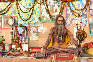 Sadhu sitting in Varanasi with offerings and religious symbols by Marco Brivio