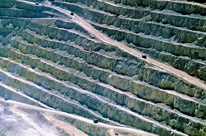 Large open pit mine showing terraced levels and mining trucks.