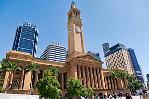 Brisbane City Hall with modern buildings and palm trees.
