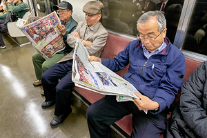 Tokyo subway commuters reading newspapers in the morning